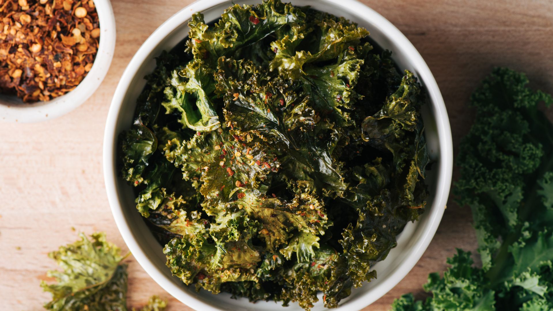 Bowl of crispy kale chips seasoned with spices showing kale benefits for healthy snacking, digestion, and weight support.