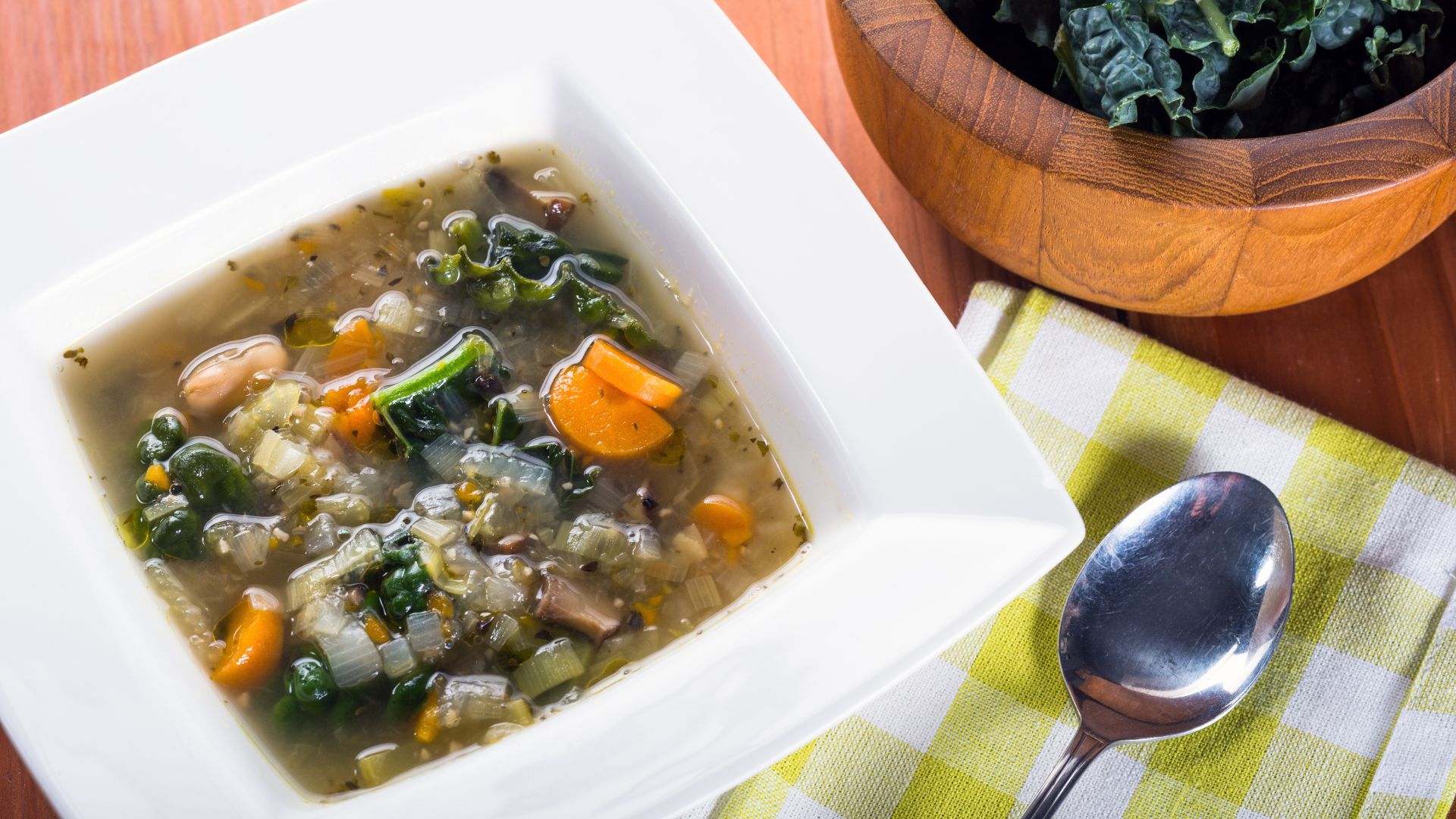 Bowl of kale vegetable soup with carrots and greens highlighting kale benefits for digestion, immunity, and healthy eating.