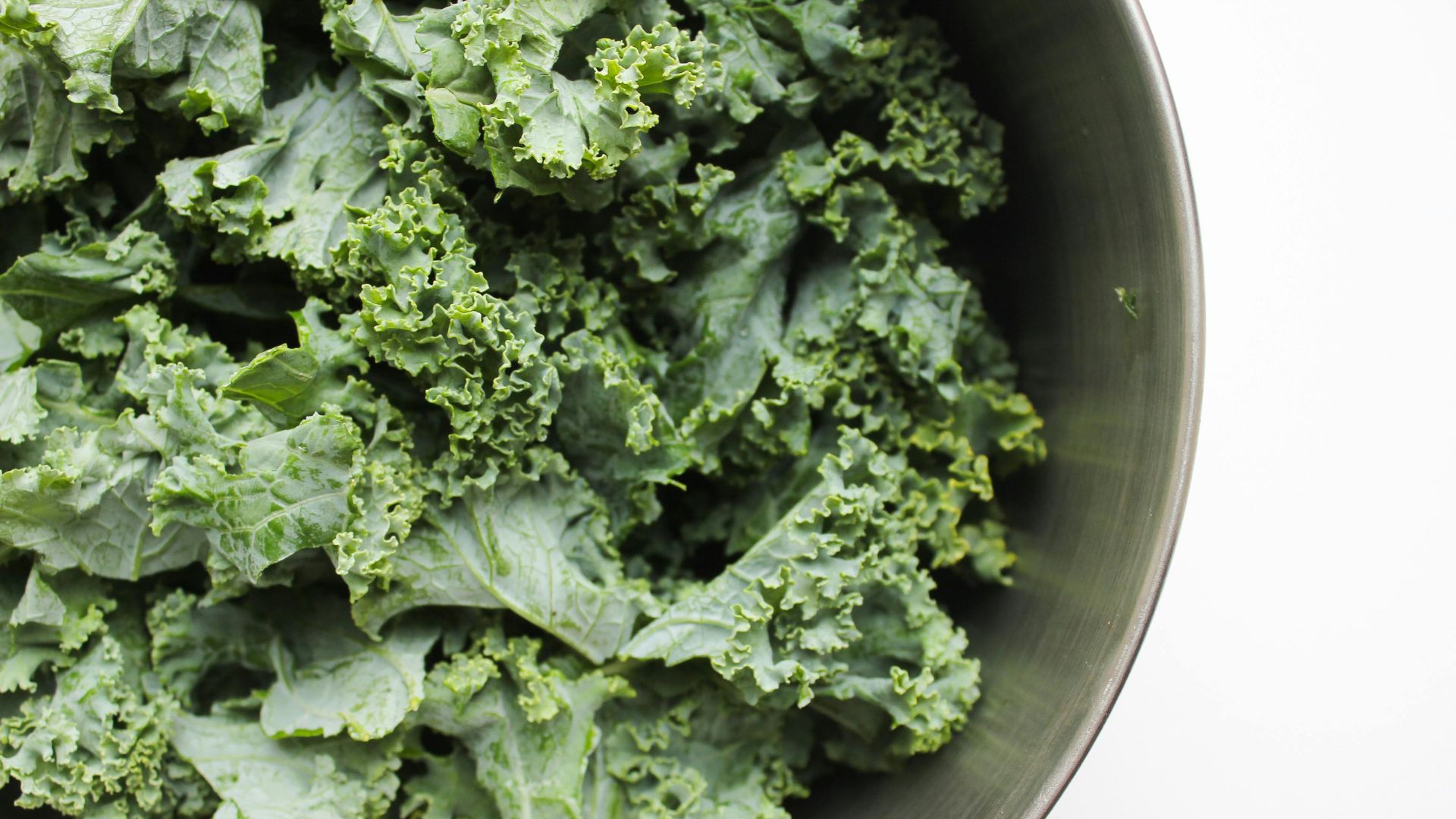 Fresh curly kale leaves in a bowl highlighting kale benefits for heart health, digestion, immunity, and healthy nutrition.