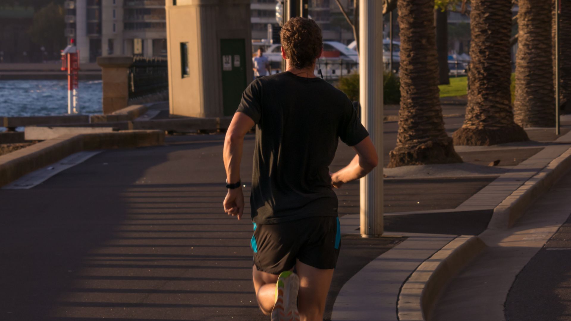 Man jogging along a waterfront path at sunrise, showing how to start running for beginners with a steady outdoor routine.