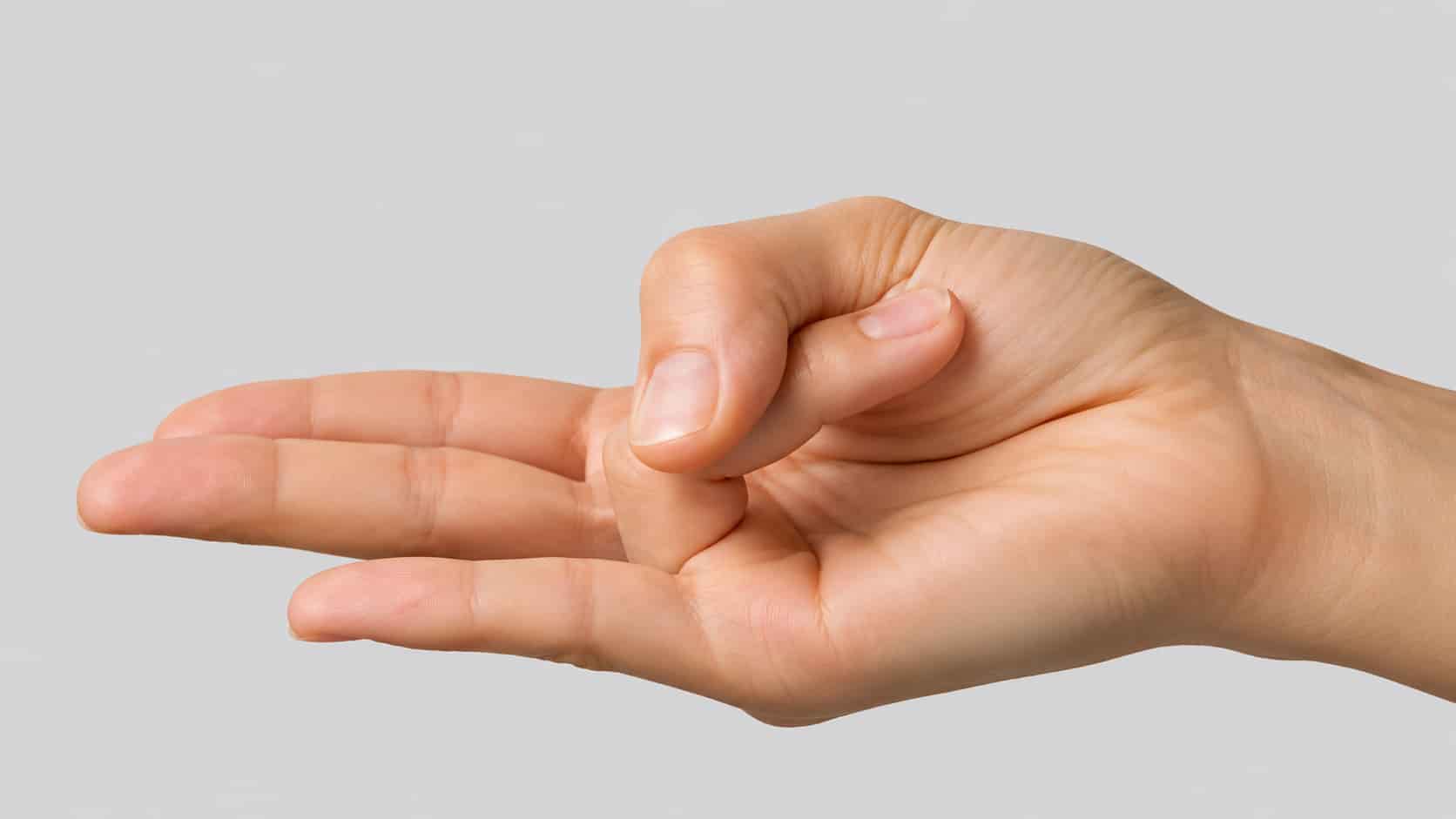 Close-up of a person's hand in Surya Mudra, with the ring finger folded down to the base of the thumb and the thumb gently pressing over it.