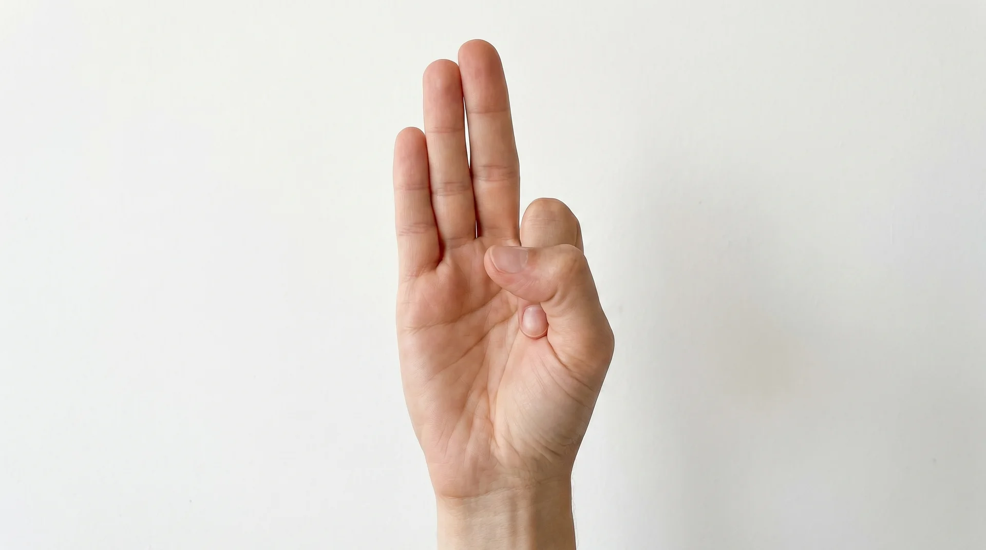 Close-up of a hand in Vayu Mudra, with the index finger folded to the base of the thumb and the thumb pressing over it.