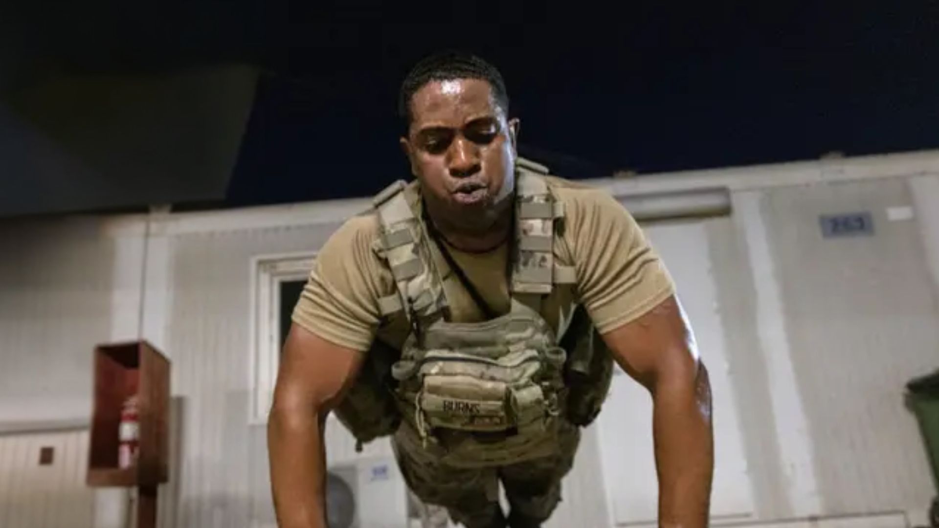 Man doing push-ups in a weighted vest during a Murph workout, showing the intense bodyweight training and endurance challenge.